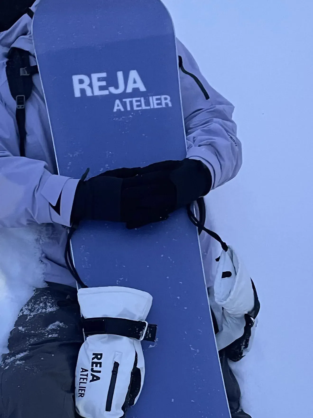 雪地中的 REJA 滑雪板、白色手套与技术服装